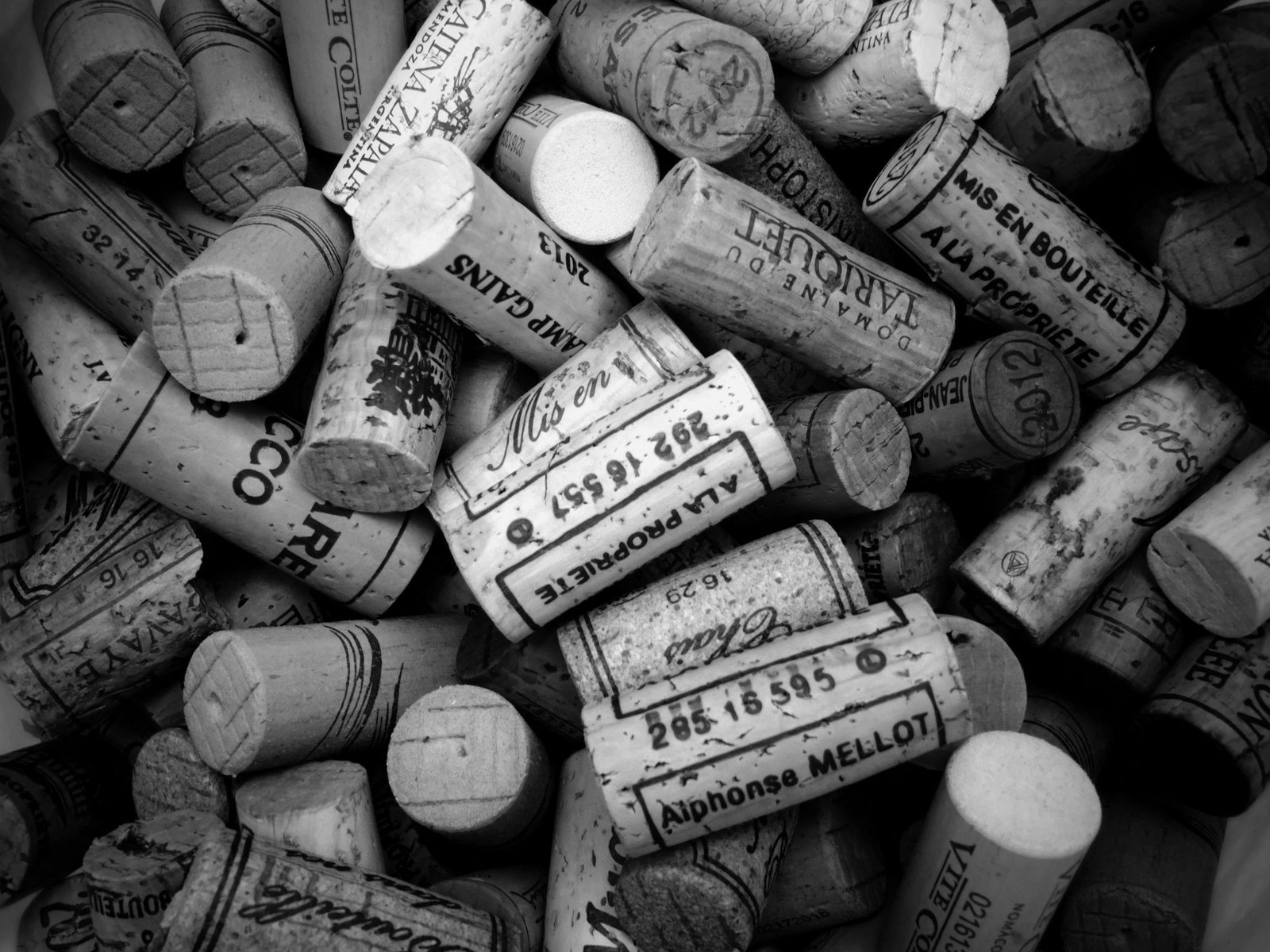 A monochrome close-up of assorted wine corks, showcasing intricate text and designs.